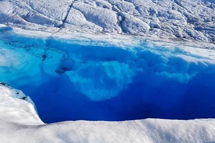 Close-up view looking down into a deep, striking blue glacial crevasse.